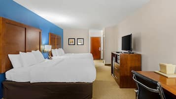 A hotel room with a large bed, a desk, a television, and a door leading to another room.