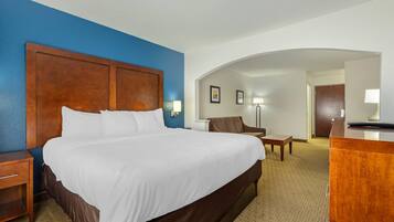 Une chambre d’hôtel avec un grand lit, un bureau, une chaise et une lampe.