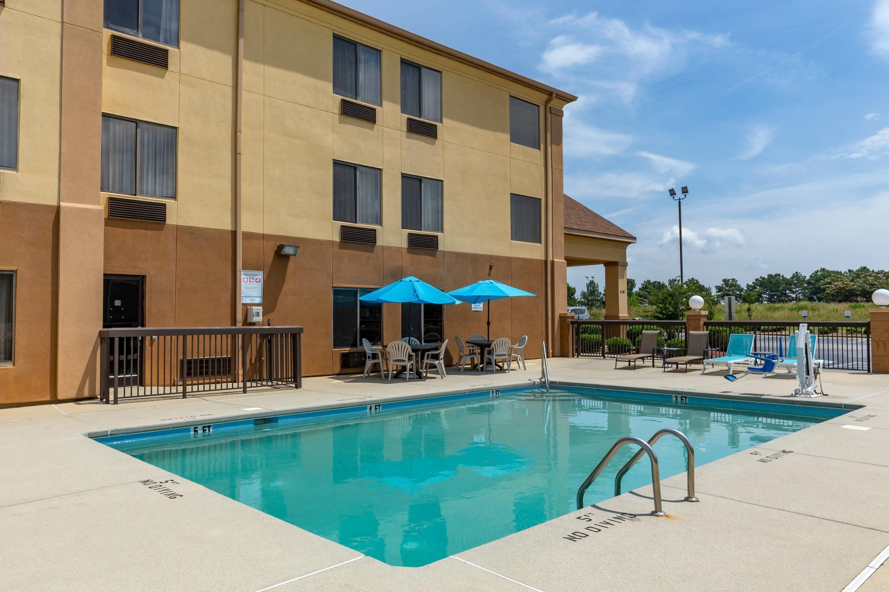 A hotel with a swimming pool, outdoor seating, and a fenced patio area.