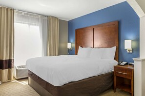 A hotel room with a large bed, a nightstand with a phone, and a window with curtains. - Comfort Inn Garner Clayton I-40 (Garner)