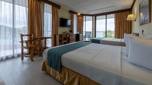 A hotel room with a large bed, a desk, a chair, a television, and a balcony with a view.