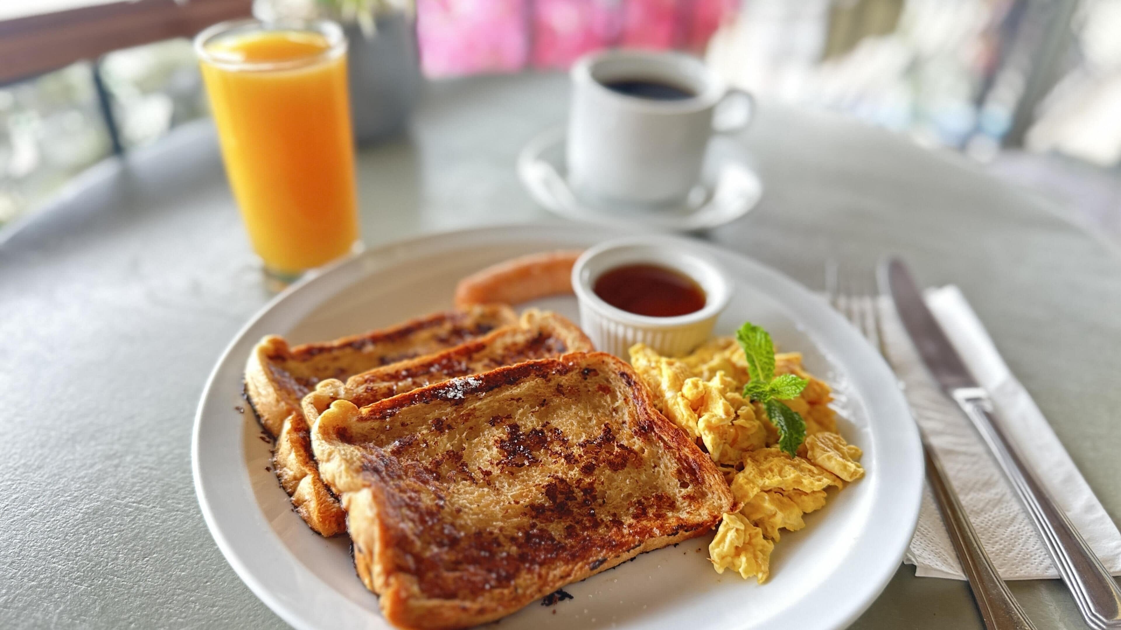 A breakfast plate with toast, scrambled eggs, and a cup of coffee.