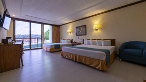 Habitación de hotel con dos camas, un escritorio, una silla y un balcón con vistas.