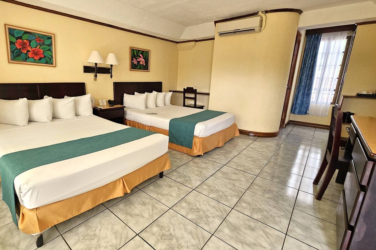 Ein Hotelzimmer mit zwei Betten, einem Schreibtisch und einem Stuhl.