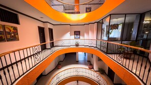 Un intérieur à plusieurs niveaux, agrémenté de rampes décoratives et d’un escalier central.