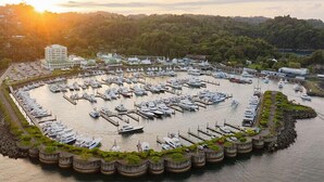 A marina with numerous boats docked, surrounded by a stone wall and greenery, with buildings in the background. - Best Western Hotel & Casino Kamuk (Quepos)