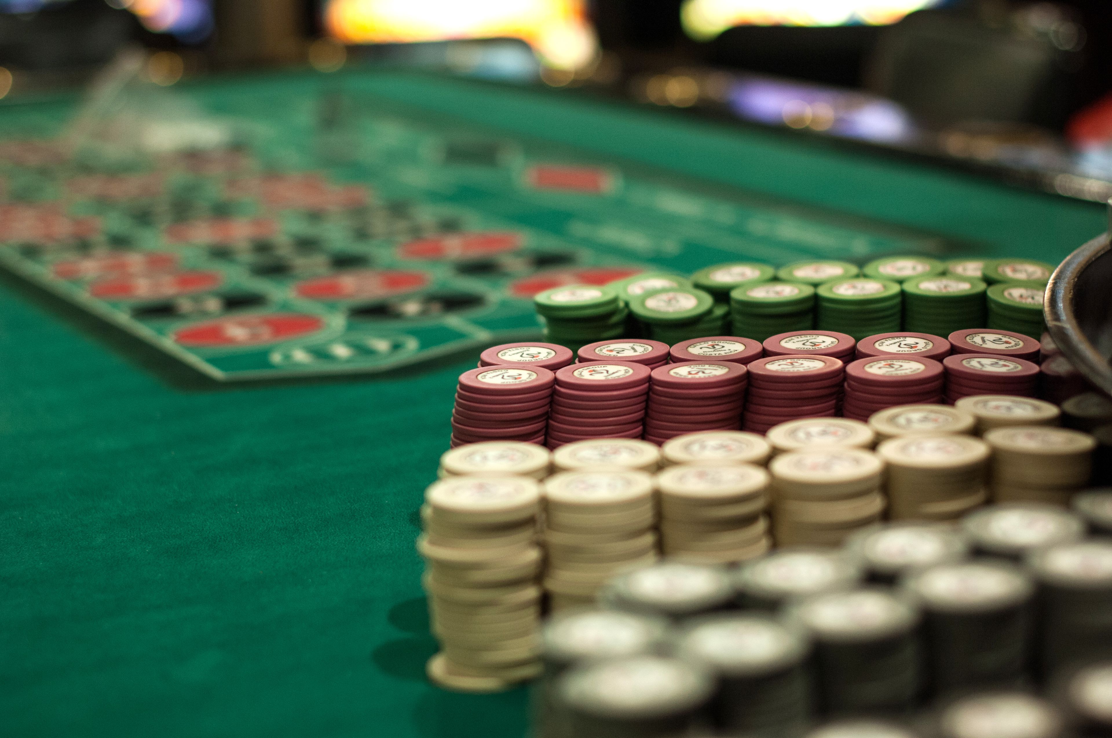 A green felt table with stacks of poker chips in various colors.