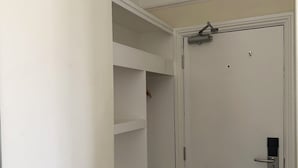 A white door with a handle and a lock, a white wall, and a carpeted floor.