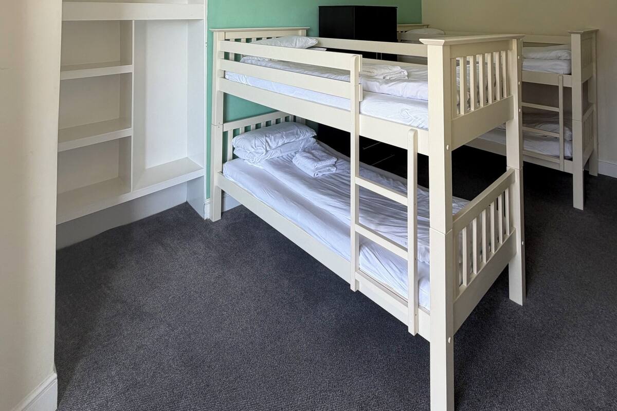 A bunk bed room with a desk and shelving unit.