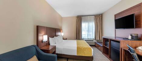 Ein Hotelzimmer mit Bett, Schreibtisch, Fernseher, Sofa und Minibar.