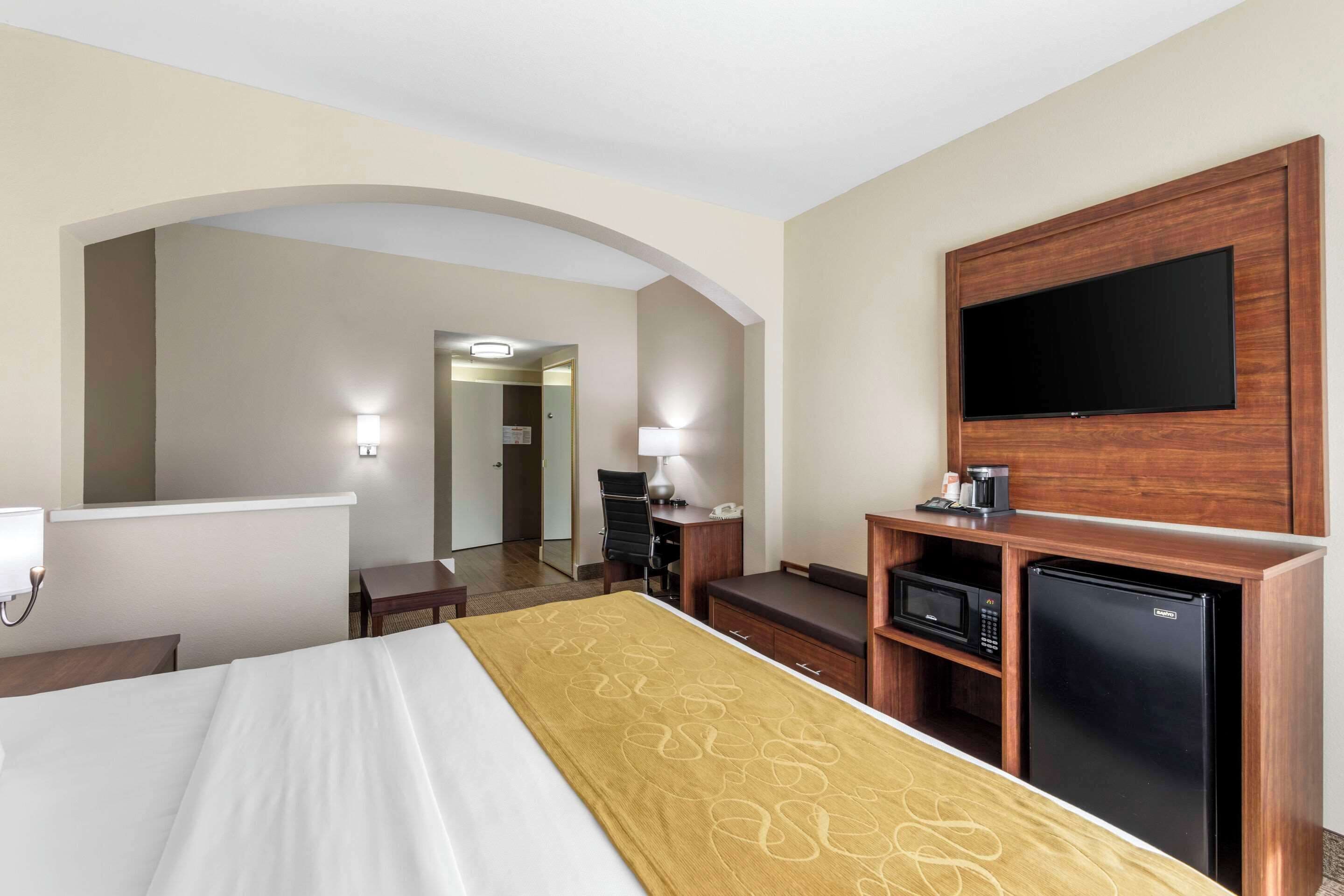 Une chambre d’hôtel équipée d’un lit, d’un téléviseur fixé au mur, d’un bureau avec une lampe, d’un four à micro-ondes et d’un réfrigérateur.