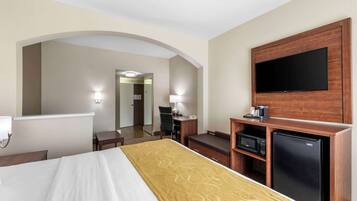 Une chambre d’hôtel équipée d’un lit, d’un téléviseur fixé au mur, d’un bureau avec une lampe, d’un four à micro-ondes et d’un réfrigérateur.