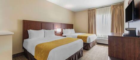 A hotel room with two beds, a desk, a television, and a window with curtains.
