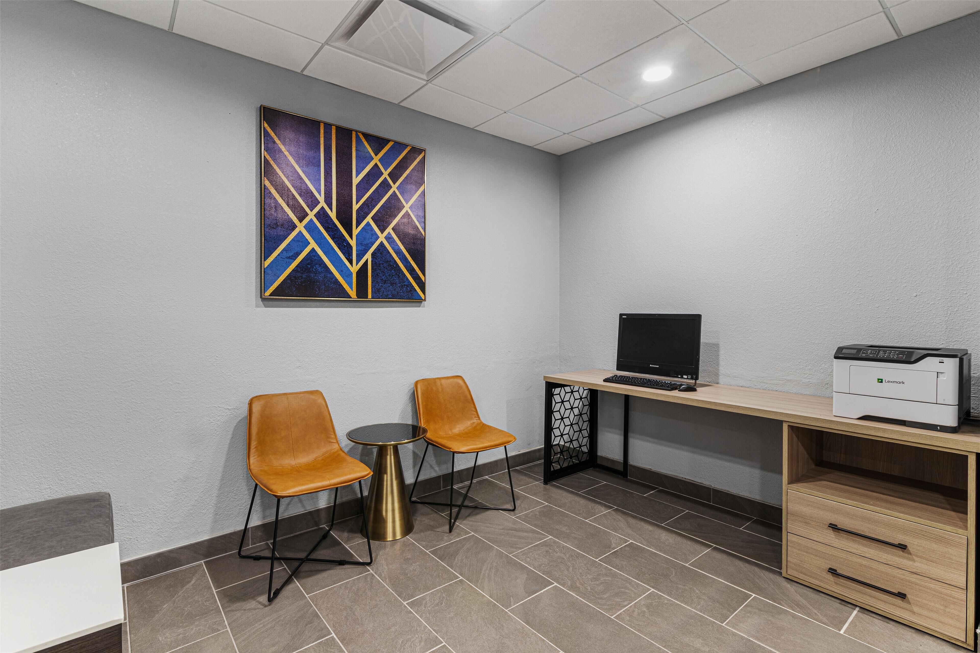 A small office area with two chairs, a desk with a printer, and a large abstract painting on the wall.
