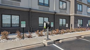 A building with multiple windows and a parking area with electric vehicle charging stations.