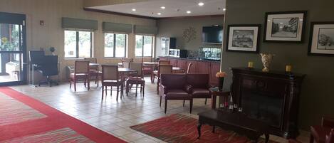 A spacious lobby with a red carpet, multiple seating areas, a fireplace, and framed pictures on the walls.