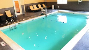 An indoor swimming pool with clear water, marked depth lines, and a ladder. There are lounge chairs along the wall and a door leading outside. - Holiday Inn Express & Suites Smithfield - Providence by IHG (Smithfield)