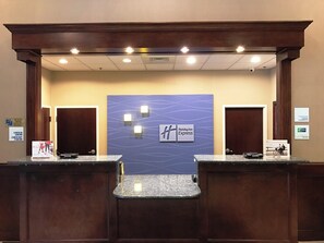 Un comptoir d’accueil avec une enseigne Holiday Inn Express, deux portes et un guichet d’enregistrement.