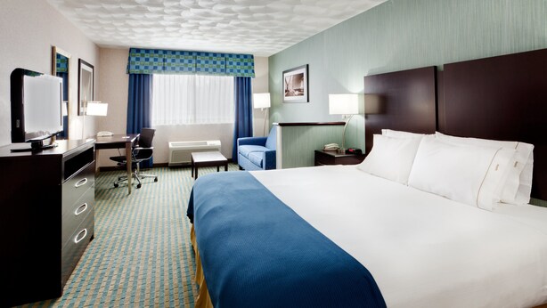 A hotel room with a large bed, a desk with a chair, a television, and a desk lamp. - Holiday Inn Express & Suites Smithfield - Providence by IHG (Smithfield)