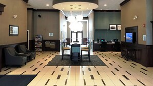 A lobby with a reception desk, seating area, and a television screen.