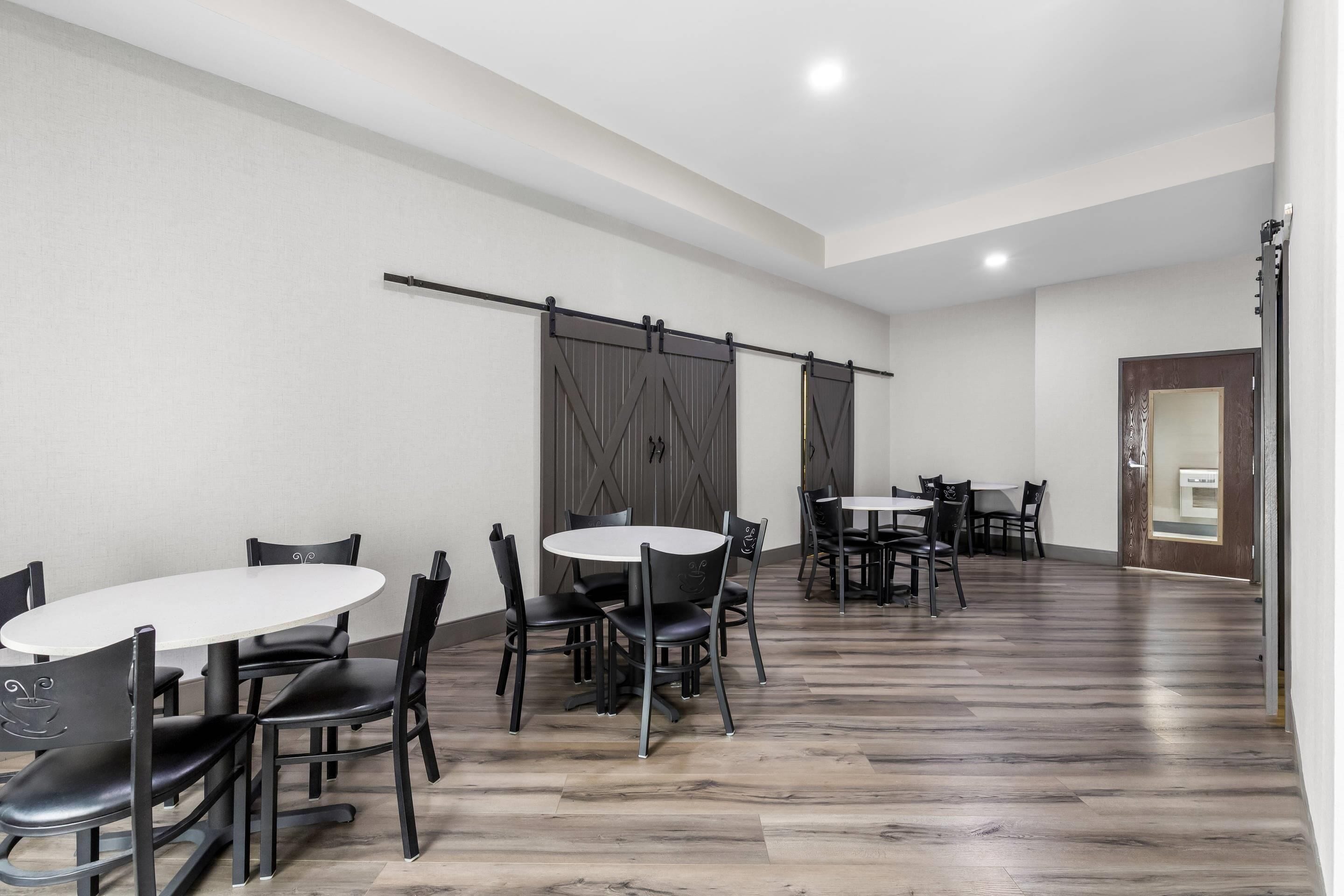 Una habitación amplia con una mesa larga y sillas, una puerta corredera estilo granero y suelo de madera.