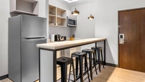 Eine moderne Küche mit einem grauen Kühlschrank, einer Mikrowelle und einer Holztür.