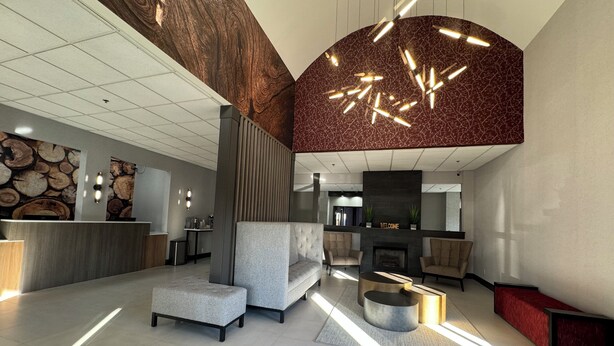 Eine moderne Lobby mit einer Rezeption, einer Sitzecke und einem Kamin.