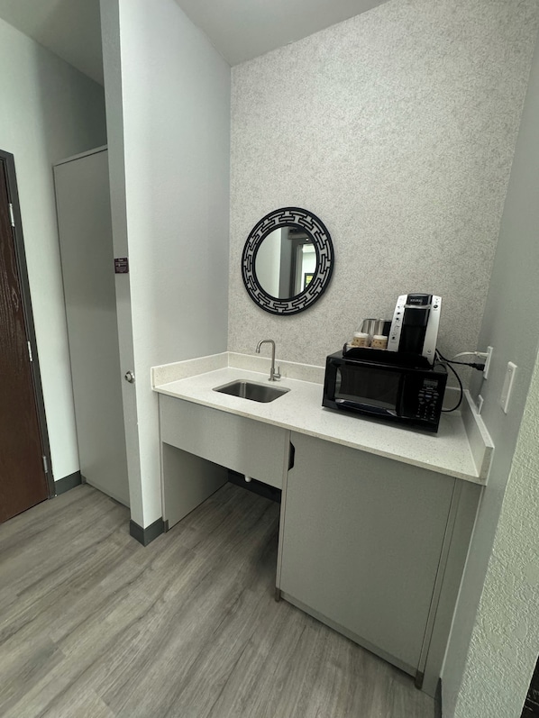 A compact kitchenette with a sink, a microwave, and a coffee maker.