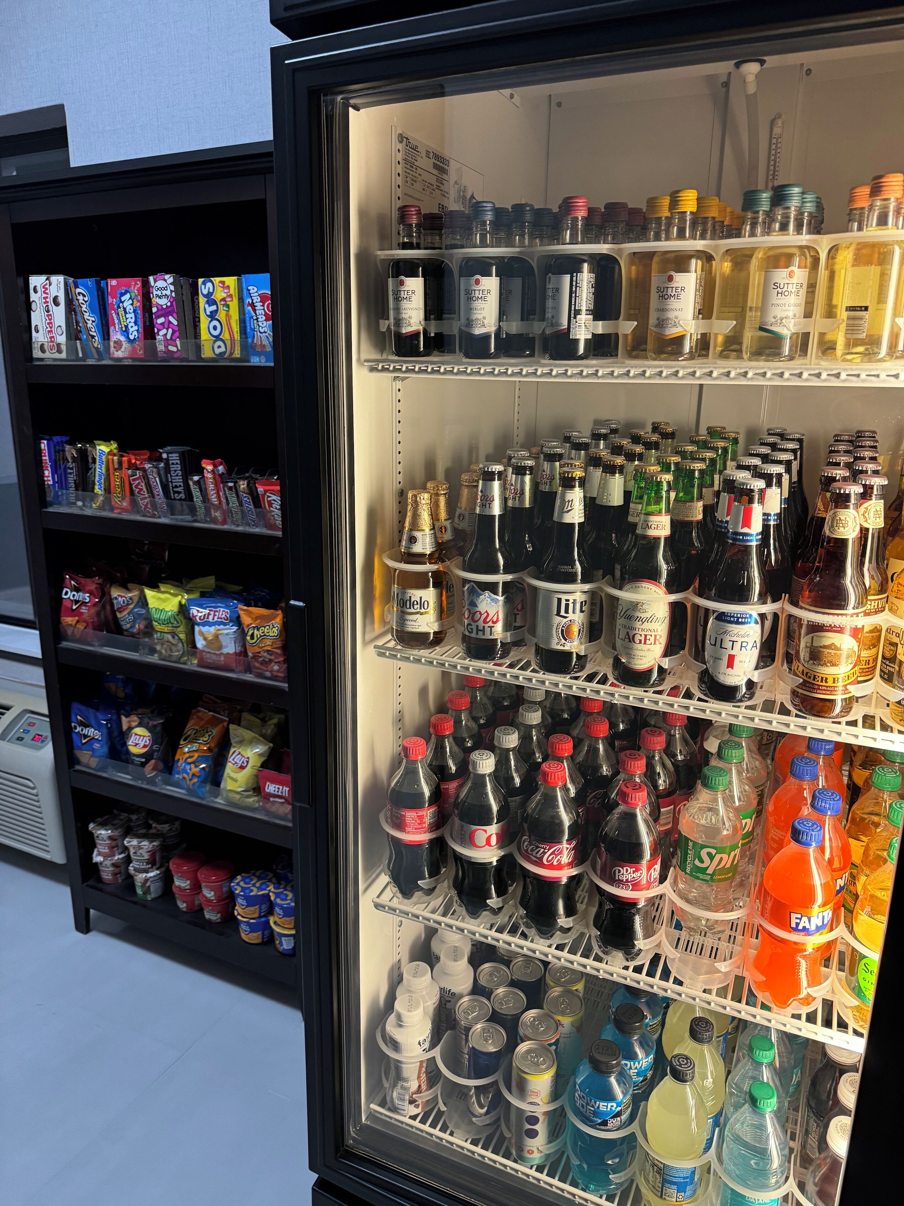 Un présentoir réfrigéré contenant diverses boissons, collations et condiments.