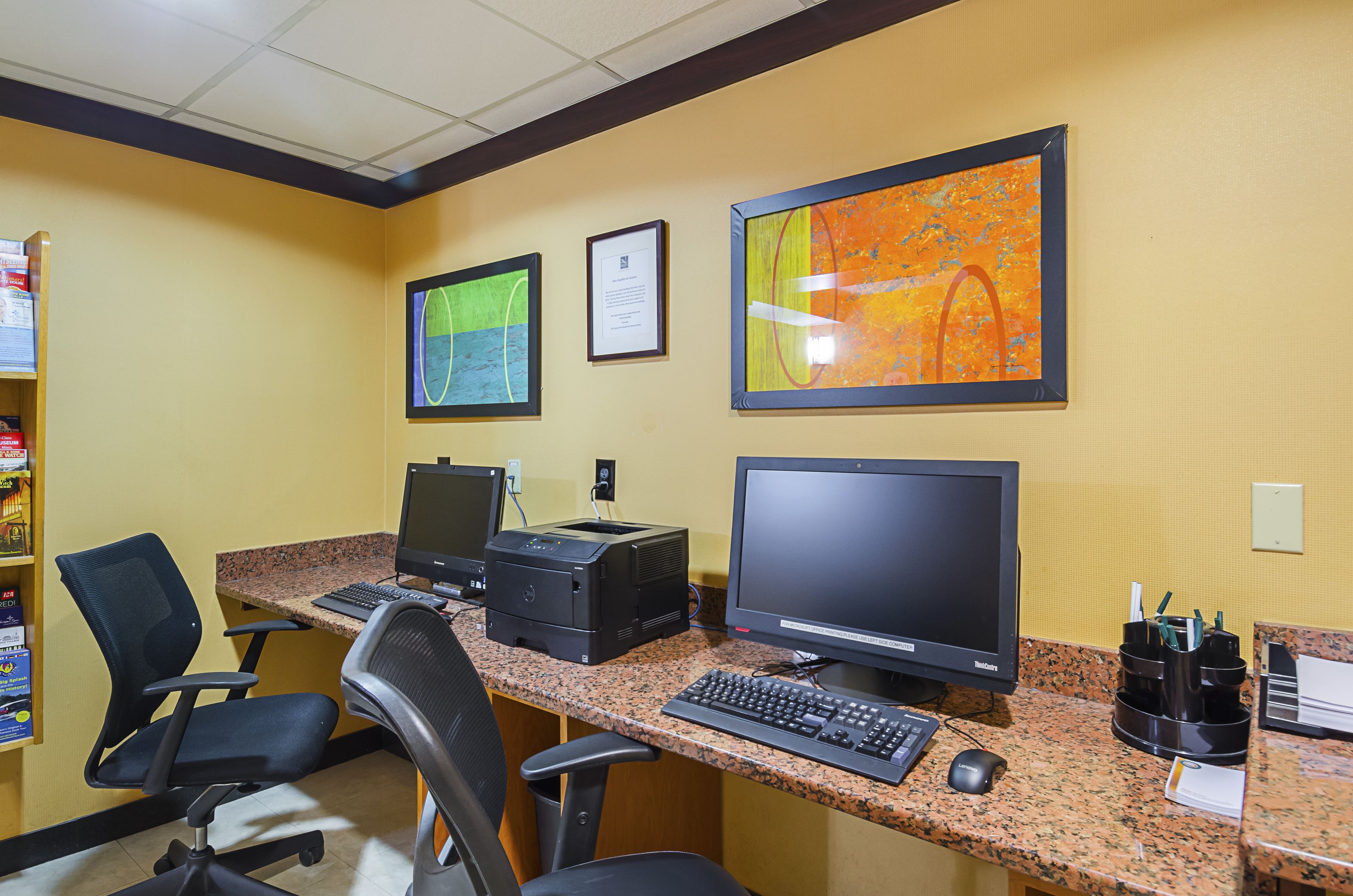 A workspace with two computers, a printer, and office chairs.