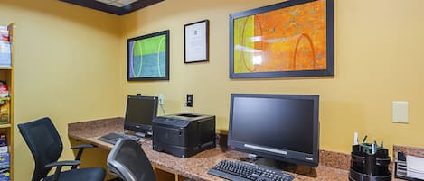 Um espaço de trabalho com dois computadores, uma impressora e cadeiras de escritório.