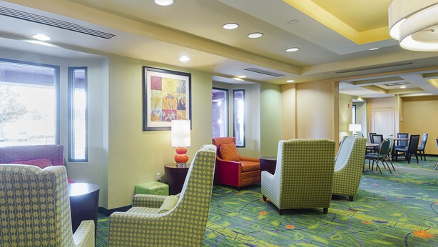 A hotel lobby with multiple seating areas, a dining table, and a large window providing natural light. - Quality Inn Boston - Revere (Revere)