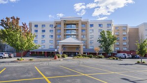 A hotel with a central entrance, multiple floors, and a parking lot with marked spaces. - Quality Inn Boston - Revere (Revere)