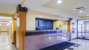 A hotel reception area with a reception desk, a clock, and a sign indicating a pet-friendly policy. - Quality Inn Boston - Revere (Revere)