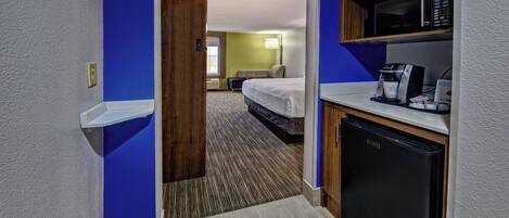 Ein Hotelzimmer mit Küchenzeile, einem Bett und einem Badezimmer.