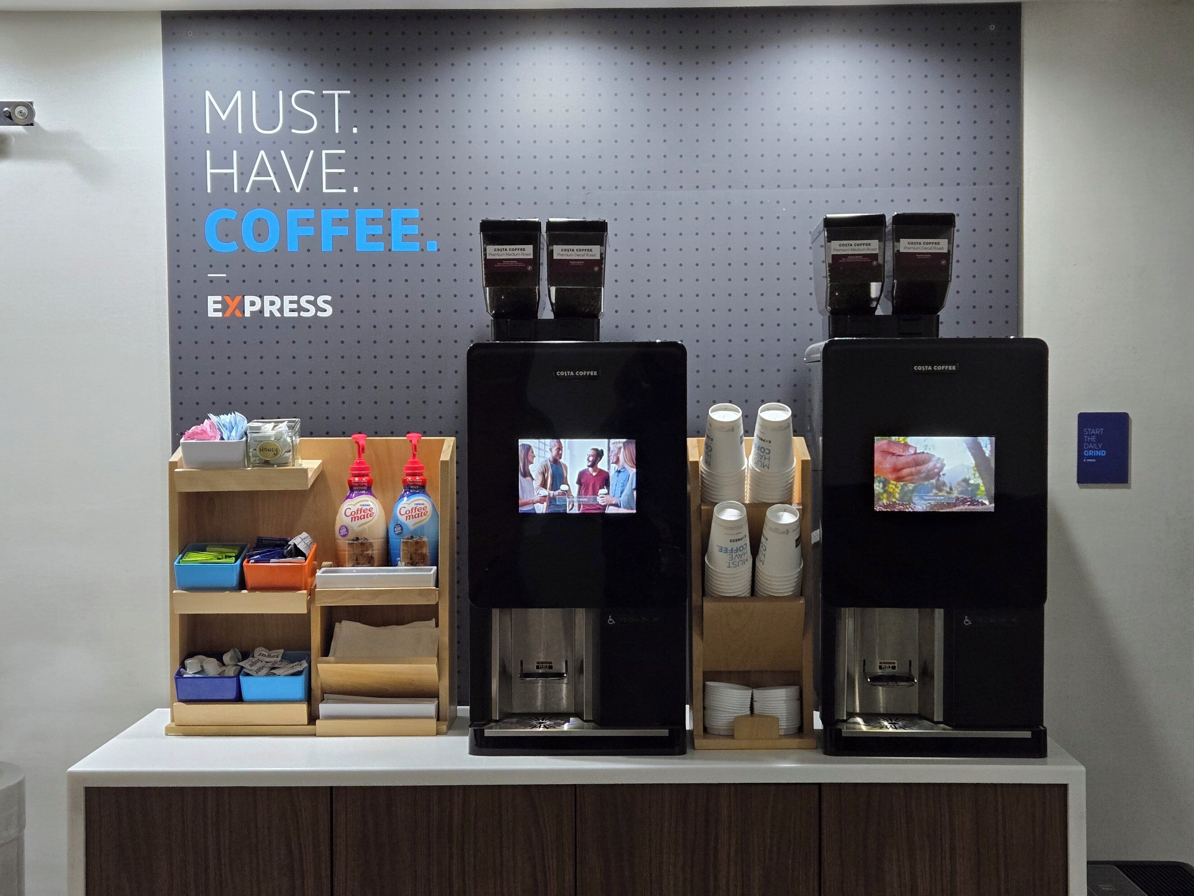 Una estación de café con dos máquinas de espresso, tazas de café y un letrero que dice 'MUST. HAVE. COFFEE. EXPRESS'.