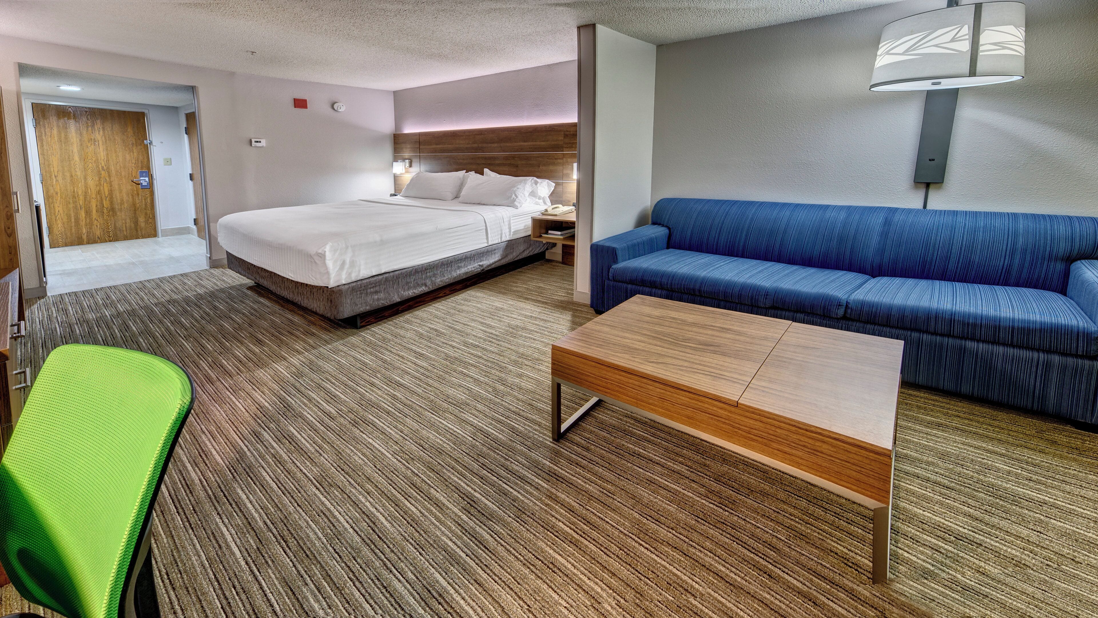 Una habitación de hotel con una cama, un sofá, una mesita de café y un banco.