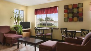 Una sala de estar con televisor, dos sofás, una mesa de centro y un ventanal con vistas al exterior.