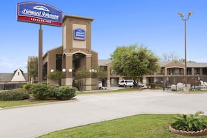 A Howard Johnson Express Inn with a prominent sign, a parking lot, and a building with a beige facade. - Howard Johnson by Wyndham Grand Prairie Near Lone Star Park (Grand Prairie)