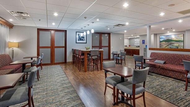 Un hall d’hôtel comprenant un espace repas, des canapés et un comptoir d’accueil.