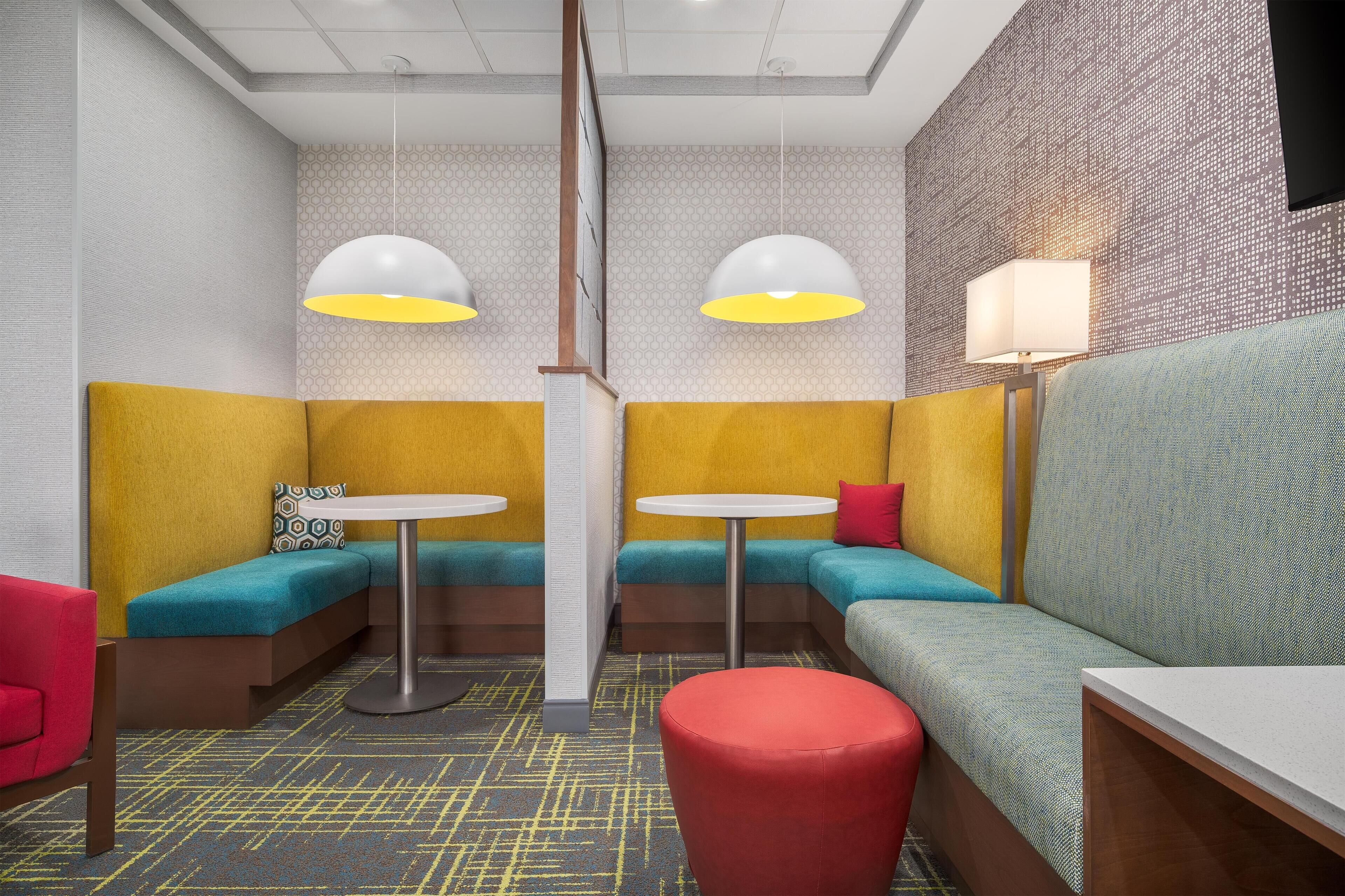 A modern lounge area with seating arrangements, pendant lighting, and a patterned wall.