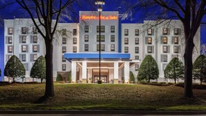 Un hôtel moderne doté d’une entrée imposante, de plusieurs étages et d’une pelouse bien entretenue avec des arbres taillés.