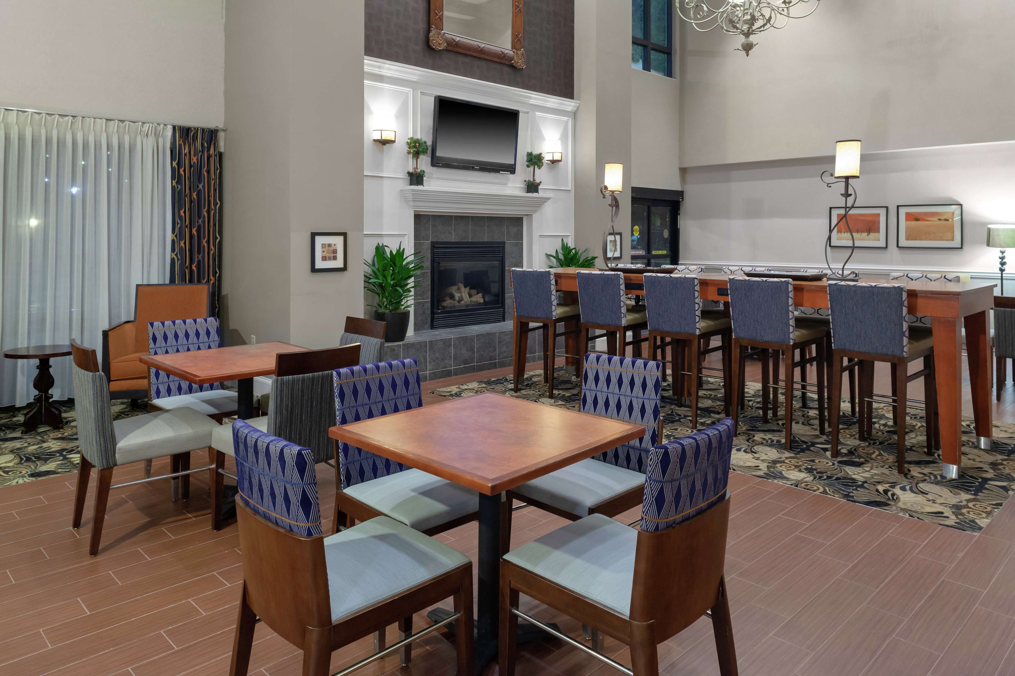 A hotel lobby with a fireplace, seating area, and a bar.