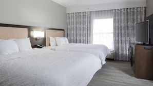 Une chambre d’hôtel avec deux lits, une télévision et un bureau.