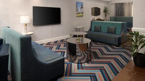 Un salon moderne comprenant un canapé, un fauteuil, une table basse et un téléviseur à écran plat fixé au mur.
