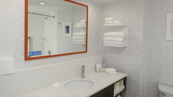 A modern bathroom with a large mirror, a sink, a toilet, and neatly arranged towels.