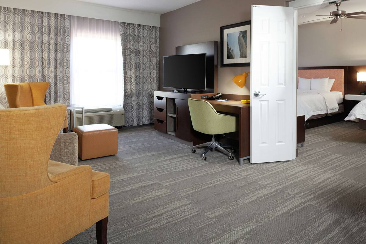 A hotel room with a bed, a desk with a computer, a television, and a chair.