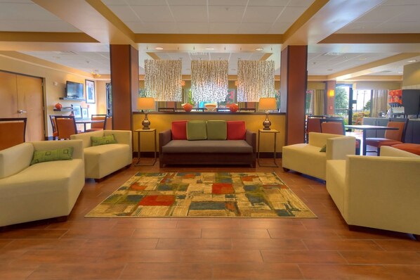 A hotel lobby with a central sofa, two armchairs, a patterned rug, and a television on the wall. - Hampton Inn San Antonio Stone Oak (San Antonio)