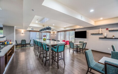 A modern kitchen with a bar area, dining space, and a large window providing natural light.