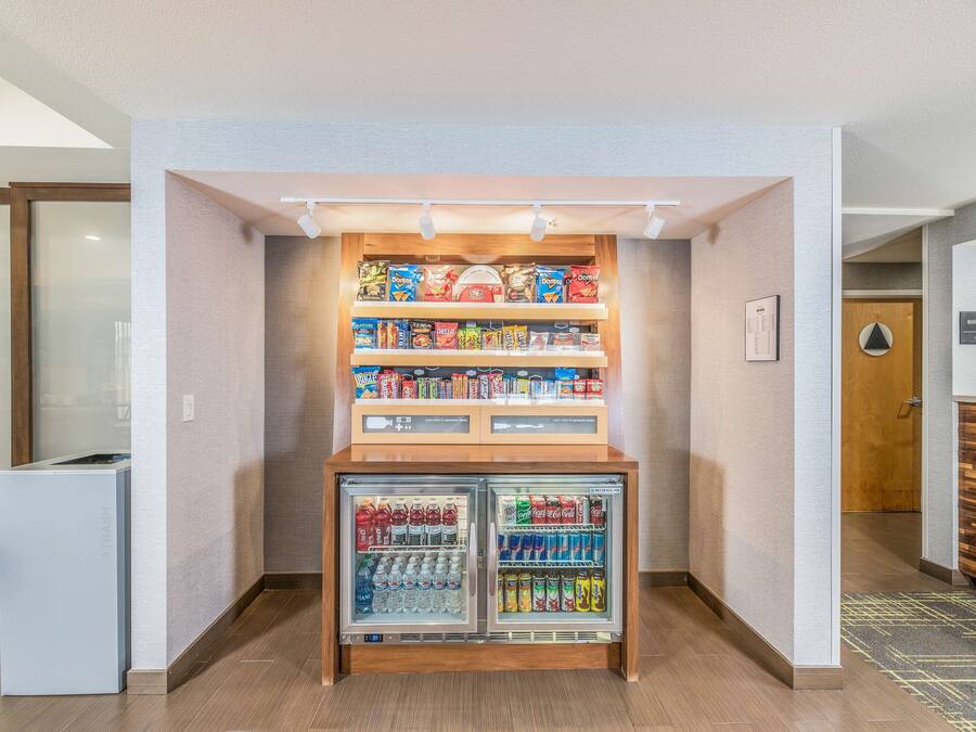 Un espace comprenant un distributeur automatique de collations et de boissons, une poubelle et un panneau indiquant l’emplacement du centre d’affaires.